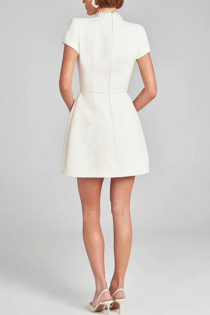 Leslie® | Exquisite and playful mini dress made of tweed fabric with beaded trim, short sleeves and pockets